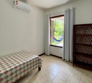 a bedroom with a bed and a large window at Apartamento Pimenta Rosa, 400m do mar, rua principal in Imbassai