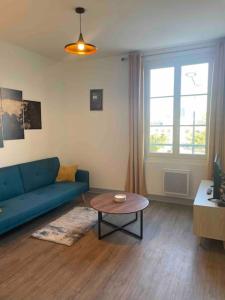 uma sala de estar com um sofá azul e uma mesa em T2 4 pers face gare SNCF Appart Hotel le Cygne 4 em Bourges