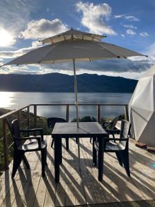 une table et des chaises avec un parasol sur une terrasse dans l'établissement Glamping Vista Lago Guatavita, à Guatavita