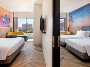 a hotel room with four beds and a tv at ibis Styles Semarang Simpang Lima in Semarang