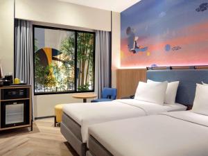 a hotel room with two beds and a window at ibis Styles Semarang Simpang Lima in Semarang