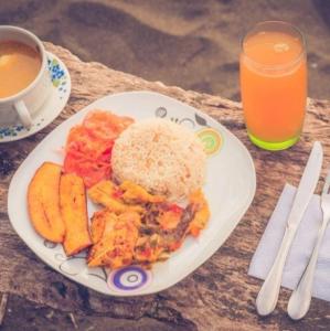 un piatto di cibo su un tavolo con una tazza di succo d'arancia di Posada Nativa Brisa y Mar a Nuquí