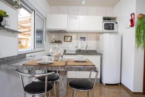 a kitchen with a counter with stools and a refrigerator at Residencial Paraíso da Gamboa in Garopaba