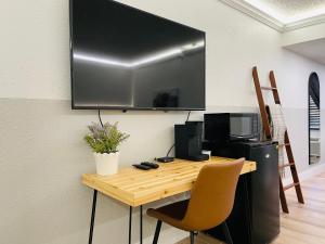 a television hanging on a wall with a table and chair at Cactus Cove Inn and Suites in Amarillo