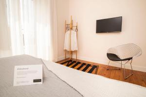 um quarto com uma cama, uma televisão e uma cadeira em SANMARTINA HOTEL em Becerril de Campos