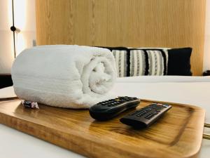 een houten dienblad met twee afstandsbedieningen op een bed bij The Westerner - Extended Stay in Amarillo