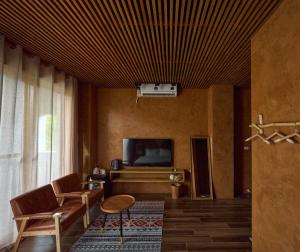 a living room with a tv and a couch and chairs at Seaside Snooze in Xiaoliuqiu