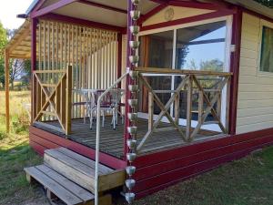 a front porch of a cabin with a table and chairs at Chalet nature et détente avec piscine, proche zoo de la Flèche et Le Mans, idéal cyclistes et familles - FR-1-410-367 in La Suze-sur-Sarthe