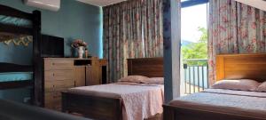 a bedroom with two beds and a balcony with a window at Casa Cica in Ubatuba +29 photos