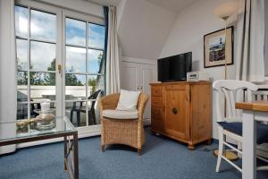 een woonkamer met een tv en een stoel en een raam bij Witt Hingst App 10 in Tinnum