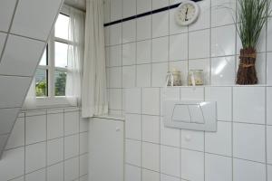 een wit betegelde badkamer met een klok aan de muur bij Witt Hingst App 10 in Tinnum +9 foto's