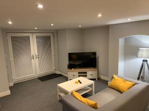 a living room with a couch and a television at Fantastic 1 Bedroom Basement flat with free parking in Sale