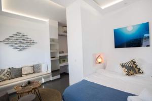 a white bedroom with a bed and a table at Jonaz Rooms & Suites in Mikonos