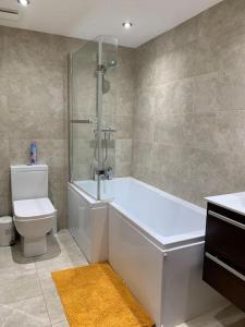 a bathroom with a white tub and a toilet at Fantastic 1 Bedroom Basement flat with free parking in Sale