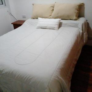un grand lit blanc avec deux oreillers dessus dans l'établissement Lourdes, à Rosario