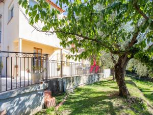 un árbol frente a una casa con una valla en Cosy vacation home with terrace, en Berre-des-Alpes