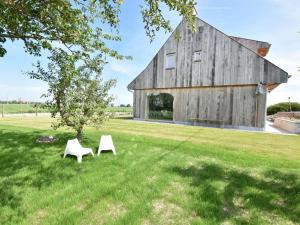 a barn with two white chairs in the grass at Beautiful Holiday Home with Terrace Garden in Diksmuide
