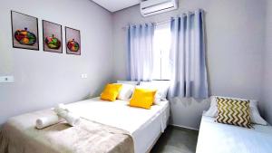 1 dormitorio con 2 camas con almohadas amarillas y ventana en Linda Casa próxima Cataratas/Aeroporto/wifi/garagem, en Foz do Iguaçu 26 fotos más