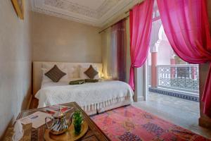 - une chambre avec un lit avec des rideaux roses et une table dans l'établissement Samira Group & Spa, à Marrakech