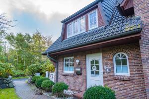 ein rotes Backsteinhaus mit einer weißen Tür in der Unterkunft Kate Kleinod in Westerland