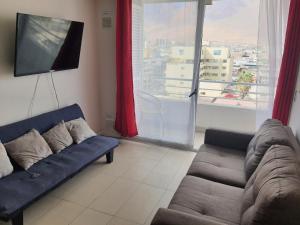 a living room with a couch and a flat screen tv at Edificio Bulnes Iquique in Iquique