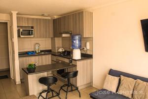 a kitchen with a counter and stools in a room at Edificio Bulnes Iquique in Iquique