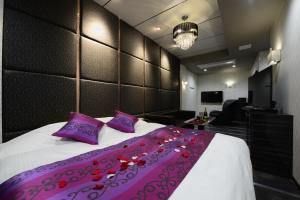 um quarto com uma cama grande e almofadas roxas em Hotel S-CUBE (Adult Only) em Bando