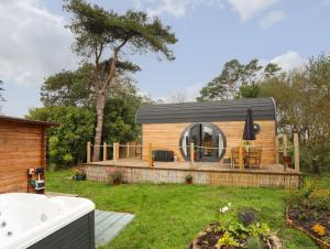 une petite maison avec un toit noir sur une cour dans l'établissement The Hideaway Pod, à Criccieth