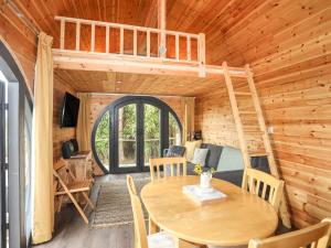 Ce chalet en bois comprend une table et une mezzanine. dans l'établissement The Hideaway Pod, à Criccieth