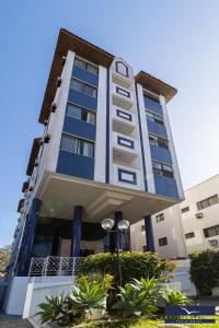 a tall building with blue windows and plants at Gaivotas Praia Hotel in Florianópolis
