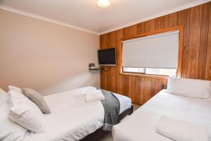 two beds in a room with a window and a tv at Jamieson Cottage in Myrtleford