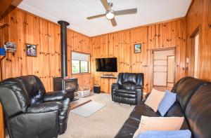 a living room with leather furniture and a flat screen tv at Jamieson Cottage in Myrtleford