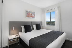 a bedroom with a large white bed and a window at Quest Mawson Lakes in Adelaide