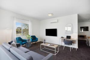 a living room with a couch and chairs and a tv at Quest Mawson Lakes in Adelaide