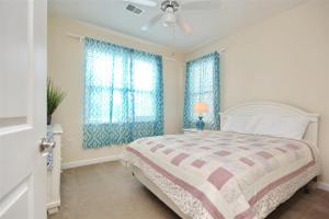 una camera con un letto e due finestre con tende blu di 2302 Crow Creek Drive a Calabash