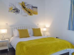 a bedroom with a bed with yellow sheets and two lamps at Y Bwthyn in Llanwinio