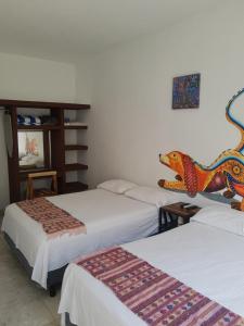 une chambre avec 3 lits et une tête de dinosaure sur le mur dans l'établissement HB Alebrijes SC, à Lachiraguigú