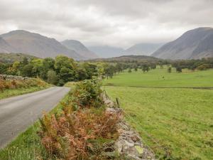 a road in a field with mountains in the background at Ravenglass Retreat in Ravenglass