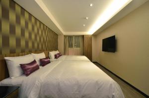 Un dormitorio con una cama grande y un televisor. en 欣欣時尚旅店松山站, en Taipéi
