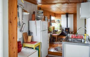 3 Bedroom Nice Home In Hyggen في Hyggen: مطبخ مع ثلاجة بيضاء في منزل صغير