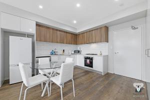 a kitchen with a glass table and white chairs at KozyGuru | Wentworthville | Kozy Style 2 Bed 2 Bath APT + Free Parking in Wentworthville