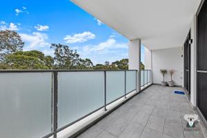 an outdoor balcony with white railing and trees at KozyGuru | Wentworthville | Kozy Style 2 Bed 2 Bath APT + Free Parking in Wentworthville