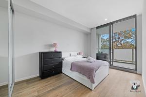 a white bedroom with a bed and a window at KozyGuru / Wentworthville / Kozy Style 2 Bed 2 Bath APT + Free Parking NWE031A in Wentworthville