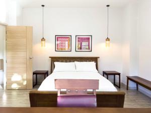 a bedroom with a bed with a bench and two tables at Chez Bure - Bure Homestay in Kanchanaburi City