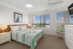 a bedroom with a bed and two windows at Riverdance Apartments in Mooloolaba