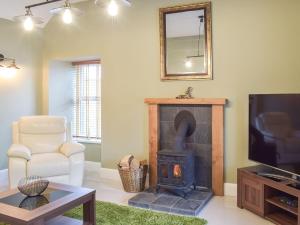 a living room with a wood stove and a tv at Dairy Cottage - Uk39522 in Maybole