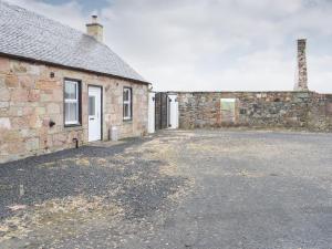 a brick building with a parking lot in front of it at Dairy Cottage - Uk39522 in Maybole