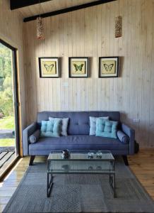 Una sala de estar con un sofá azul y una mesa de cristal. en Loft Puro Ranco, en Lago Ranco