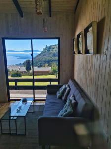 Una sala de estar con un sofá y una ventana grande. en Loft Puro Ranco, en Lago Ranco