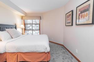 a white bedroom with a bed and a window at The best ski in ski out two bedroom condo at Aspens in Whistler